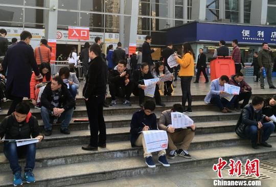 求职者席地而坐关注各类招聘信息。