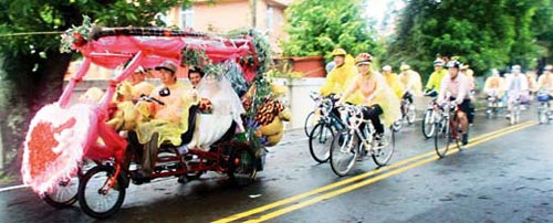 李旭嘉、洪祯彩19日在嘉义结婚,99人迎亲团在风雨中骑单车随行,新人在“礼车”上也淋得一身湿,但笑得幸福灿烂。
