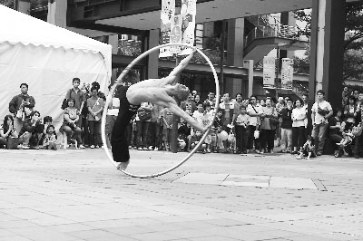 在信义商圈休闲区,街头艺人进行钢圈表演。
