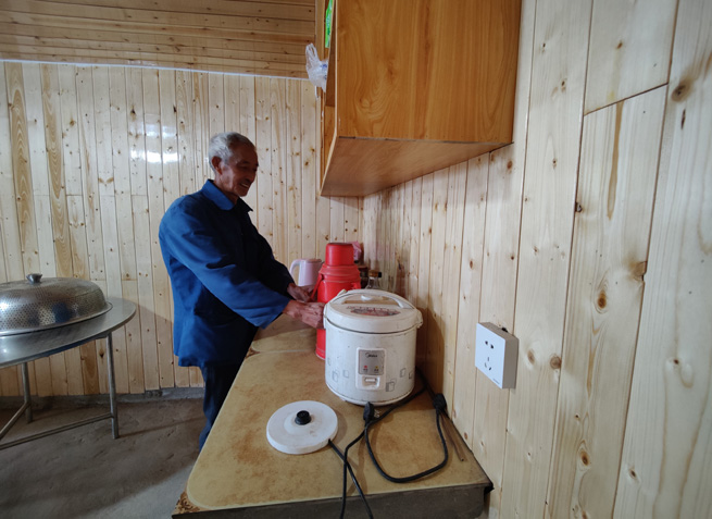 杉板装饰的屋内,老党员正热情地给客人们倒茶。徐俊聪摄