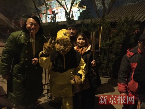 大年初一零点,雍和宫门口,已经排有超过50名香客,最前面的湖北人王先生以孙悟空造型装扮,和众人合影。新京报记者 赵力 摄