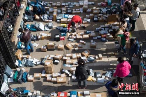 资料图:工作人员忙着分拣满地的快递。 武俊杰 摄