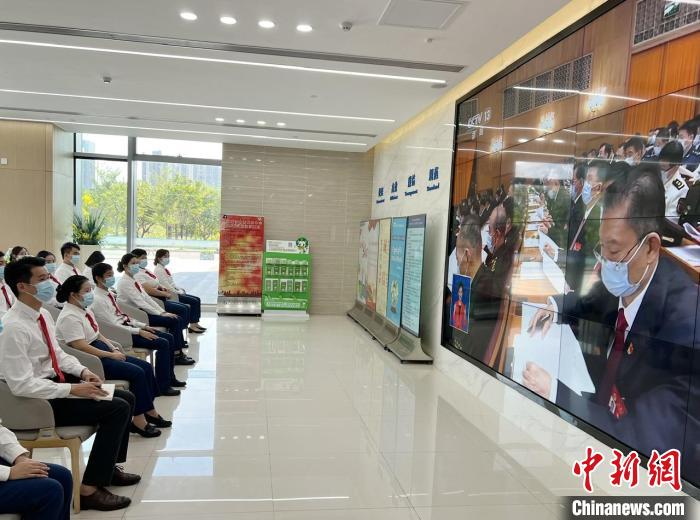 黄钊逸(第一排左一)与同事一起,通过电视收看党的二十大开幕直播。 王坚 摄