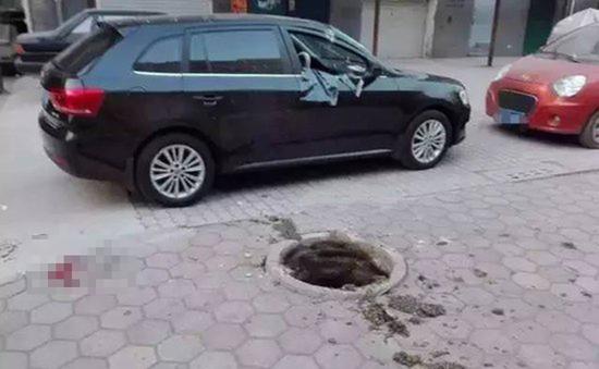 事发地点位于小区内一车库附近,井盖已经被炸得不知去向,一辆黑色轿车停在旁边,因爆炸右半部分严重变形。