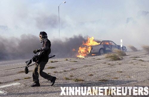 10月21日,一名新闻记者在美国加利福尼亚州马利布地区山林大火现场走过燃烧的小汽车。当天,距离洛杉矶西南约30公里的马利布地区发生山林大火,目前已造成至少500英亩的山林和数幢建筑物被毁,数百人被紧急疏散。 新华社/路透