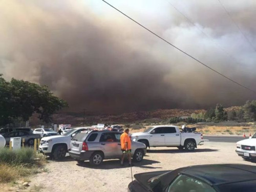 从拉斯维加斯回洛杉矶的中国游客在15号公路附近休息站休息,看得见浓烟蔽日。(美国《世界日报》)