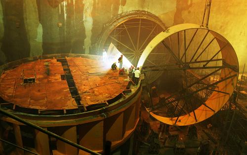 三峡地下电站机组首次3节蜗壳定位节吊装成功 5月26日,施工人员在三峡地下电站工地吊装发电机组蜗壳。当日,三峡地下电站机组首次3节蜗壳定位节吊装成功。据悉,首次吊装的为32号机组蜗壳,工程量约811.6吨。三峡地下电站机组蜗壳制造安装工期紧、任务重、施工难度大,承担该项目施工任务的葛洲坝集团机电公司通航工程设备安装处合理调配人员,优化施工方案,采取严密的质量、安全保证体系,从而大大提高了制造、安装的施工质量和施工进度。 新华社发(孙荣刚 摄)