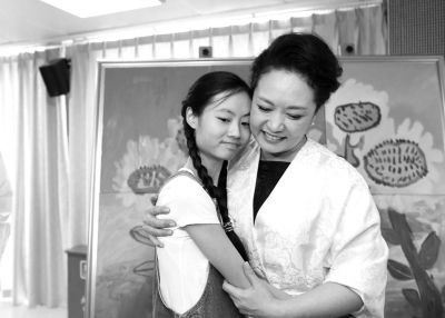 彭丽媛与孤独症儿童在《向日葵》作品前合影。图/北京市残联