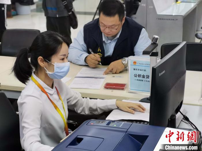 广西壮族自治区区直住房公积金管理中心工作人员为梁洲辅办理公积金贷款。 蒋雪林 摄