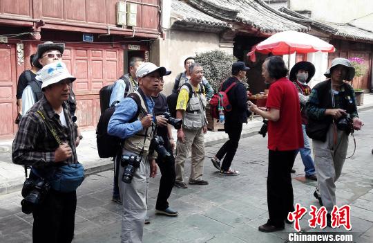 云南省摄影家协会副主席徐晋燕(红衣)在云南巍山古城向两岸摄影家介绍古城渊源。 周志鸿 摄