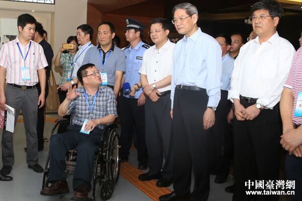 中共中央台办、国务院台办主任张志军与福建省残联副理事长杨小波（坐轮椅者）亲切交流。