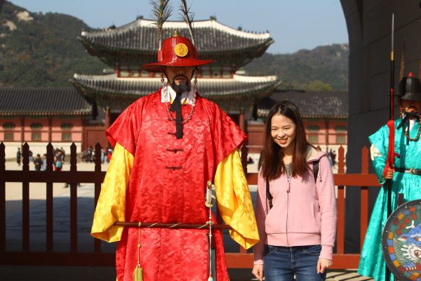 在韩国首尔景福宫外，中国游客与韩国守城门将合影。