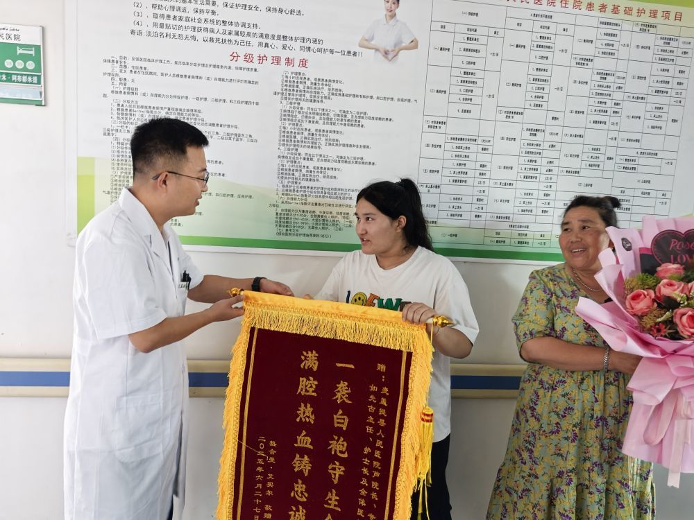 6月27日,在麦盖提县人民医院,患者热合曼·艾买尔的亲属将一面锦旗和一束鲜花送到了日照援疆医生魏鑫的手中。(新华社记者 顾煜 摄)
