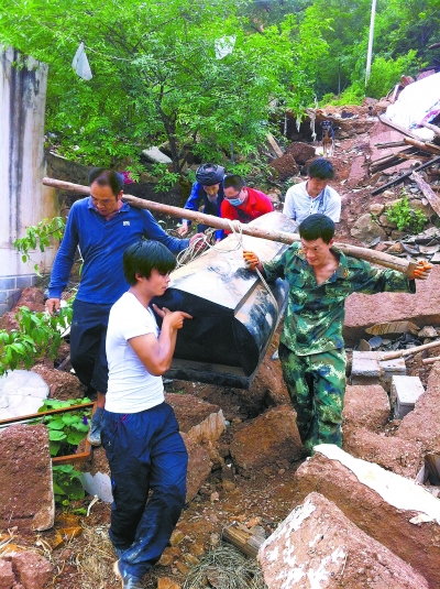 志愿者帮老人从废墟中抬出棺木