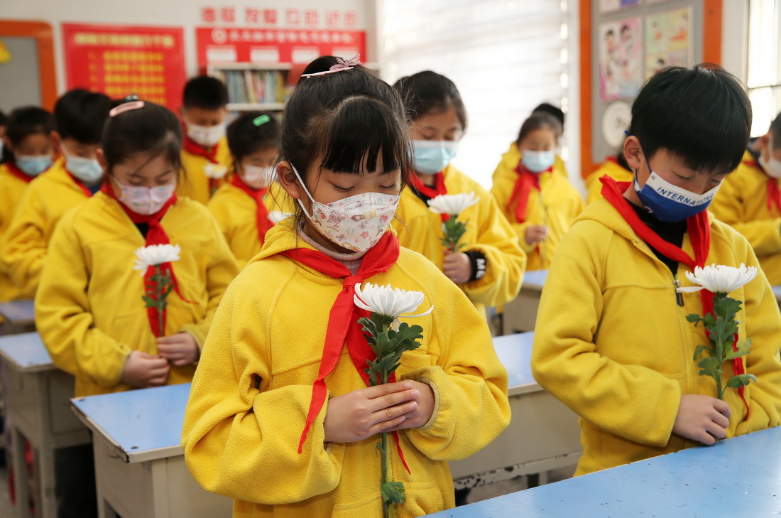 安徽省淮北市首府实验小学学生手持鲜花通过教学网络向英烈默哀
