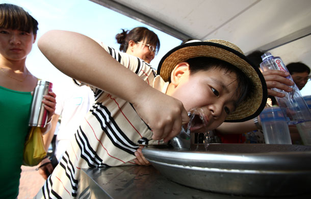 7月18日,来自北京的9岁小游客杨志圣在世博园饮水点喝水.